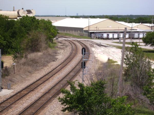 Looking north at the double track mainline to Tulsa from the Line Street overpass. Liberty Glass plant on the right. That's TSU trackage on the right