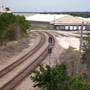 Looking north at the double track mainline to Tulsa from the Line Street overpass. Liberty Glass plant on the right. That's TSU trackage on the right